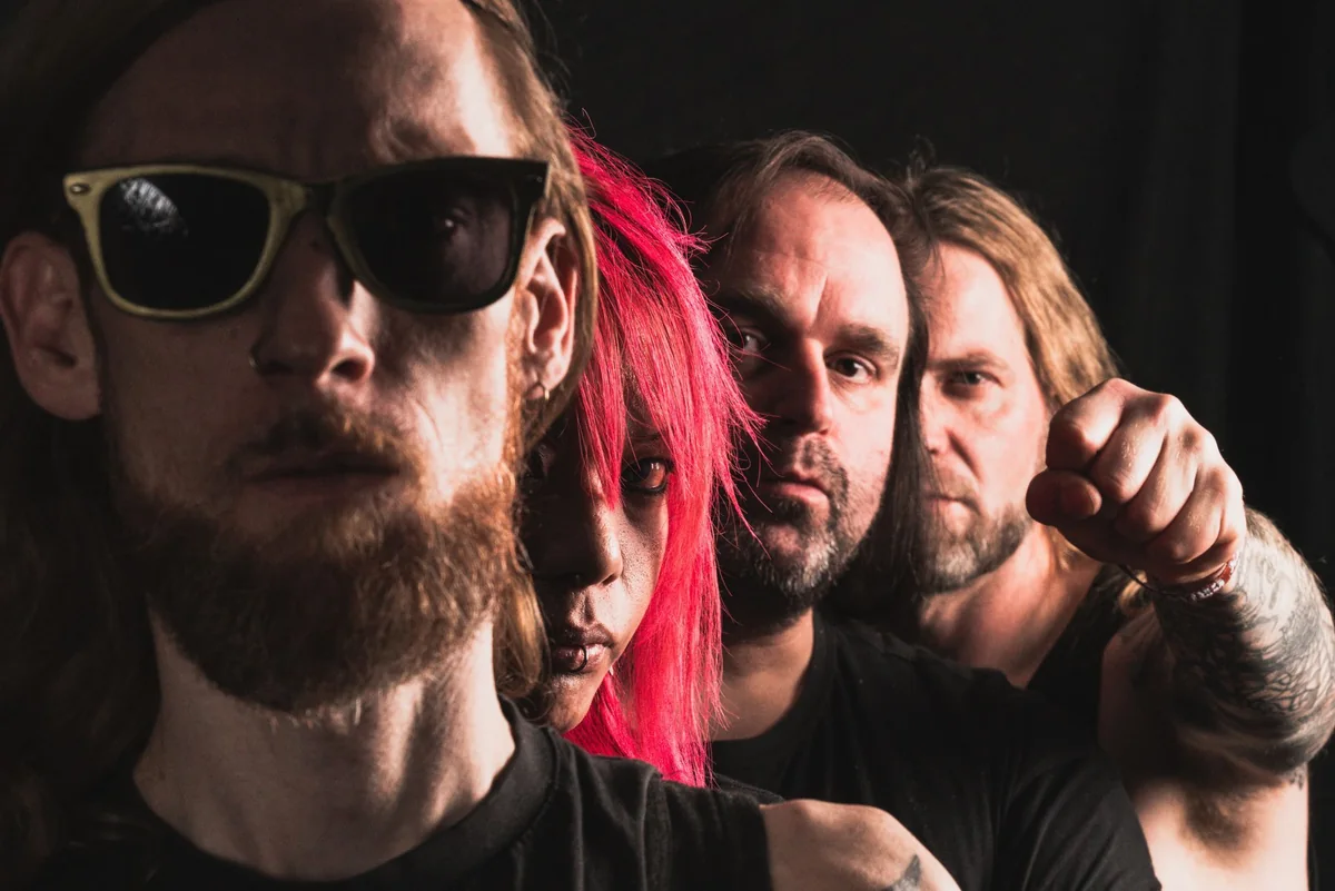 Die Band Extinct steht hintereinander vor schwarzem Hintergrund