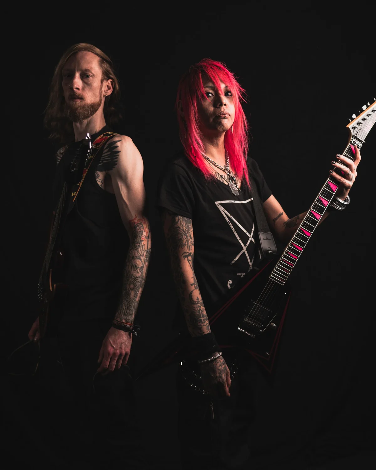 Zwei Bandmitglieder stehen Rücken an Rücken mit Gitarre
