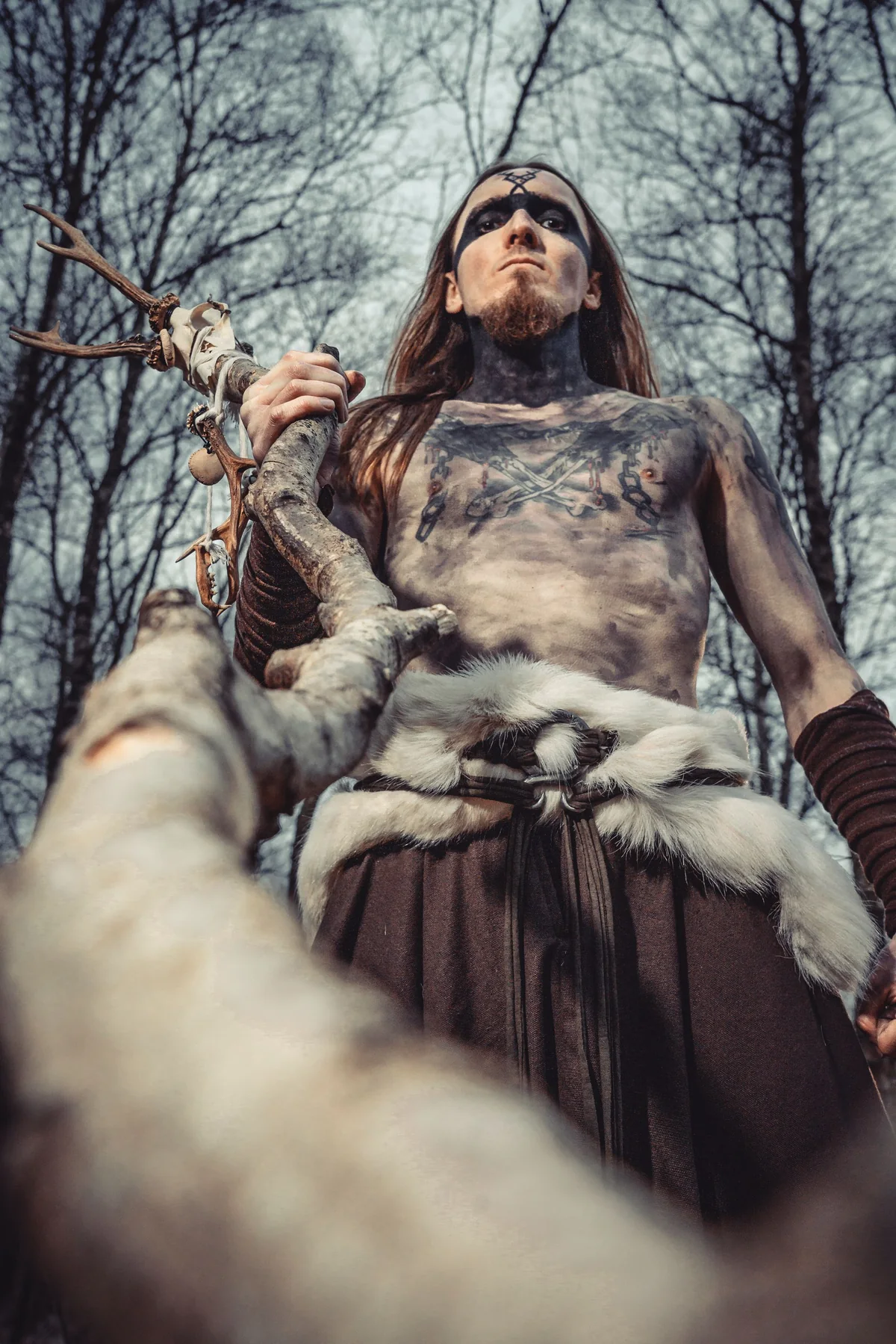 Musiker in Fellkleidung im Wald, von unten fotografiert