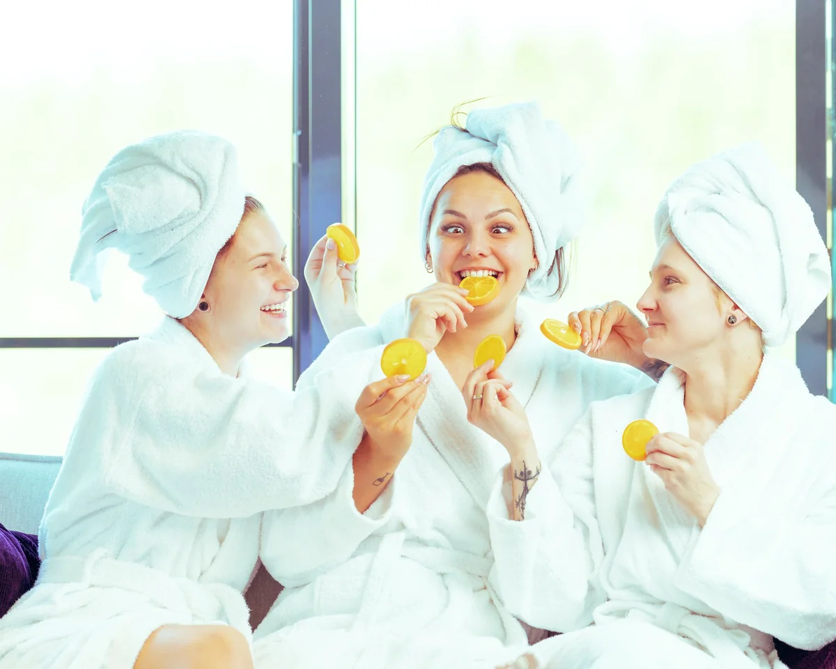 Drei Frauen lachen mit Orangenscheiben in den Händen