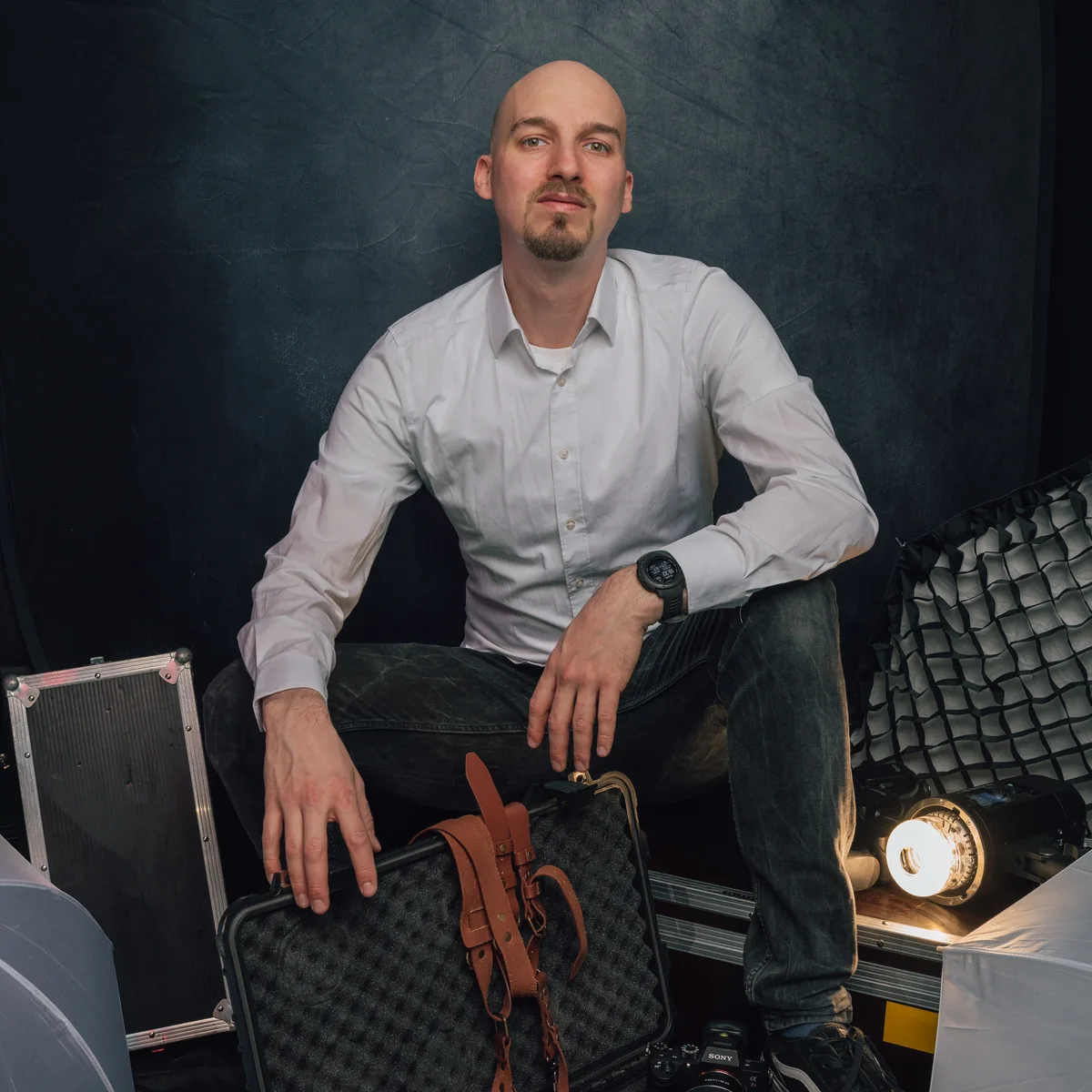 Sitzendes Portrait mit Kameratasche im Studio