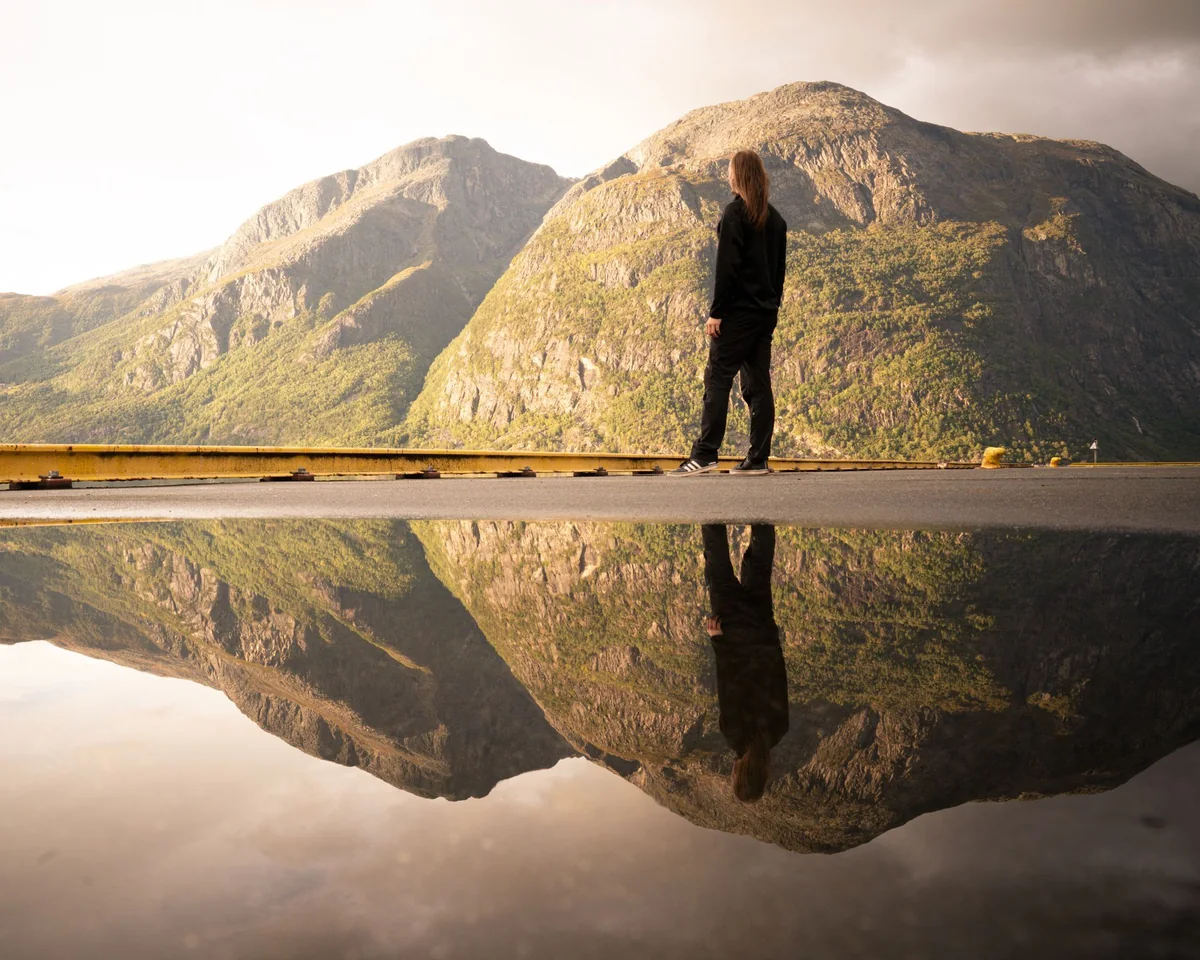 Eine Person am Bergsee spiegelt sich im Wasser