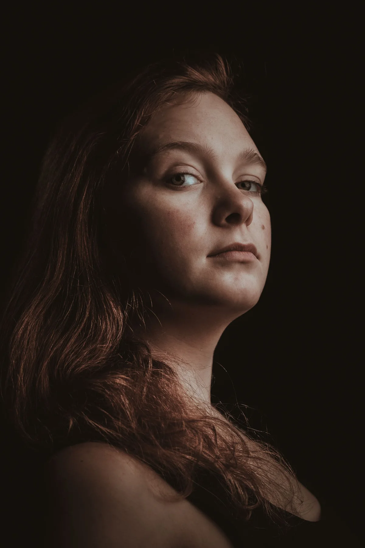 Frauenportrait im weichen Seitenlicht vor dunklem Hintergrund