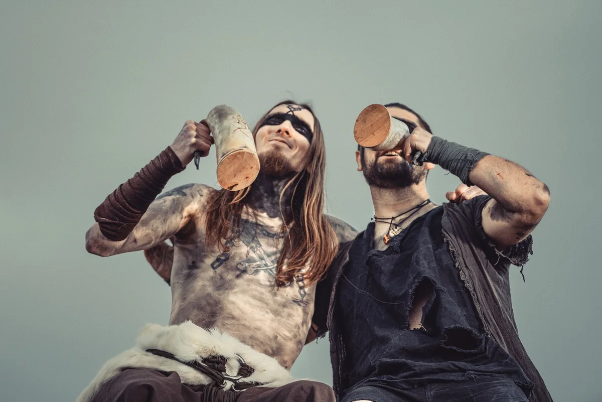 Zwei Musiker trinken aus Trinkhörnern