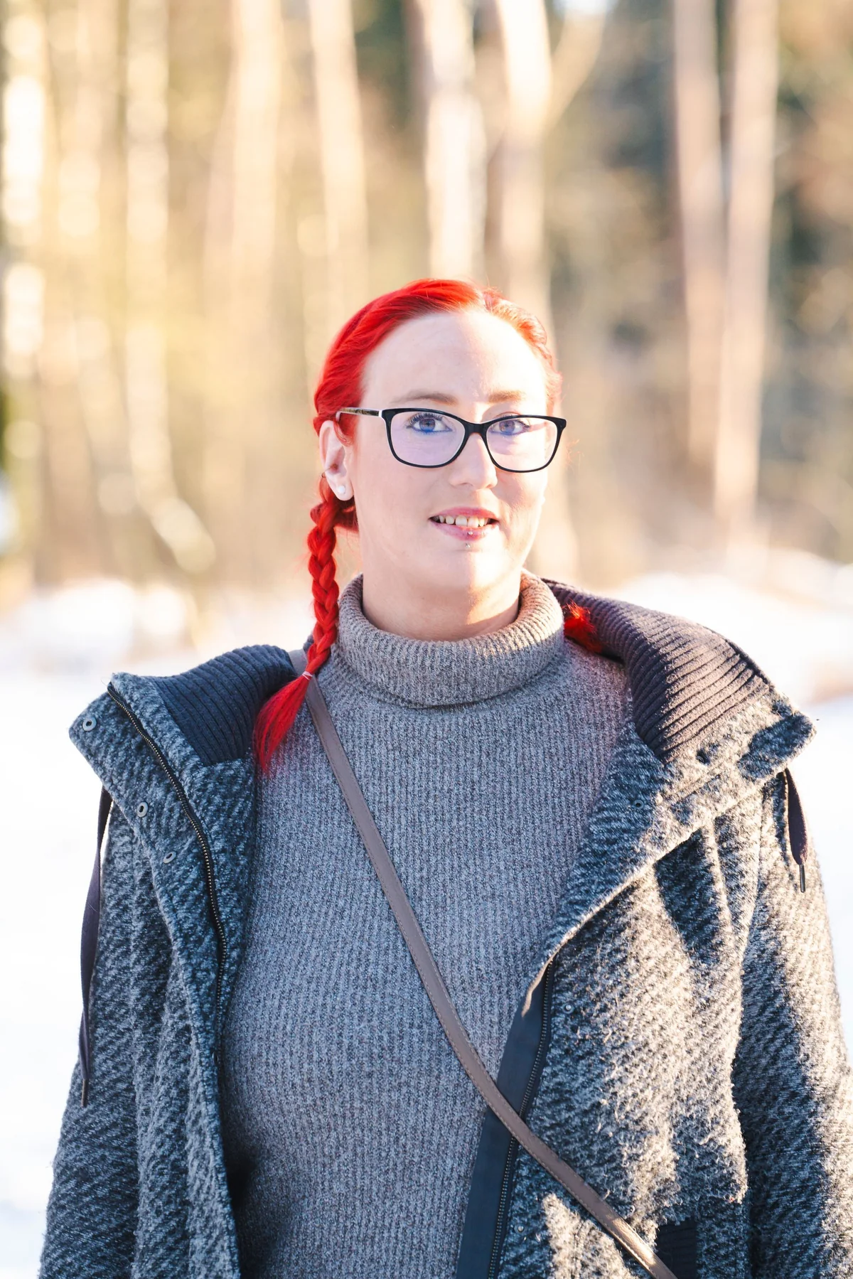 Marina mit roten Zöpfen auf einem verschneiten Waldweg